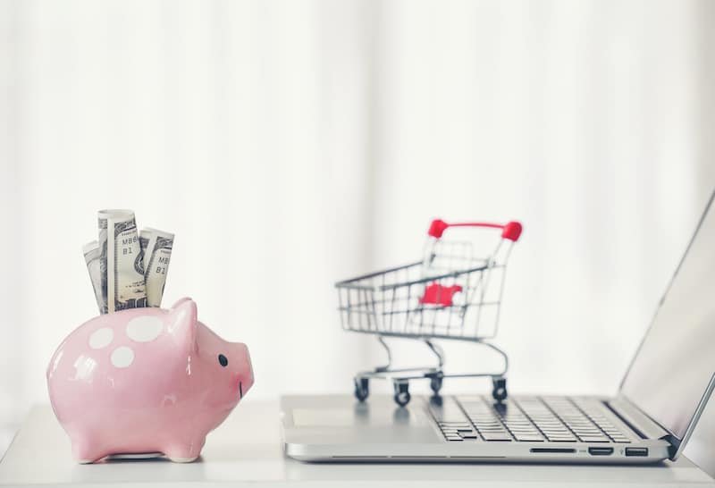 shopping cart and piggy bank with laptop on the desk