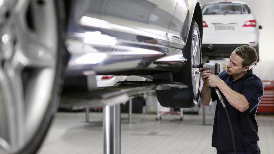A man standing in front of a car and repairing