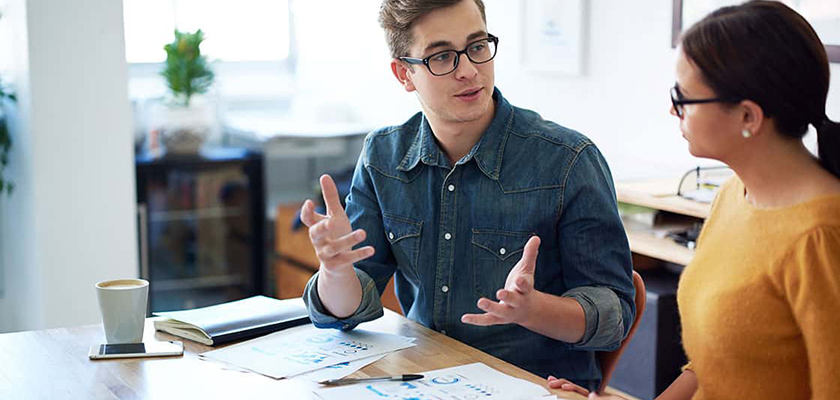 A man and a woman sitting at a table using a laptop